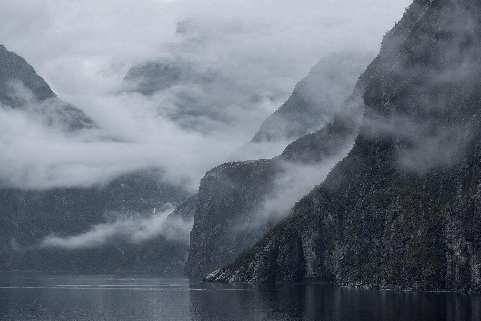 Misty fjord with steep cliffs